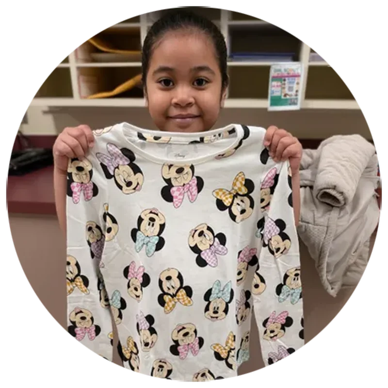 A student smiles holding a new shirt from Operation School Bell